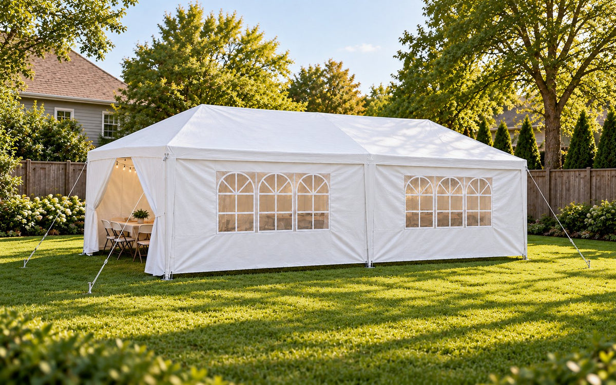A white backyard party canopy with sidewalls shelters a table and chairs.